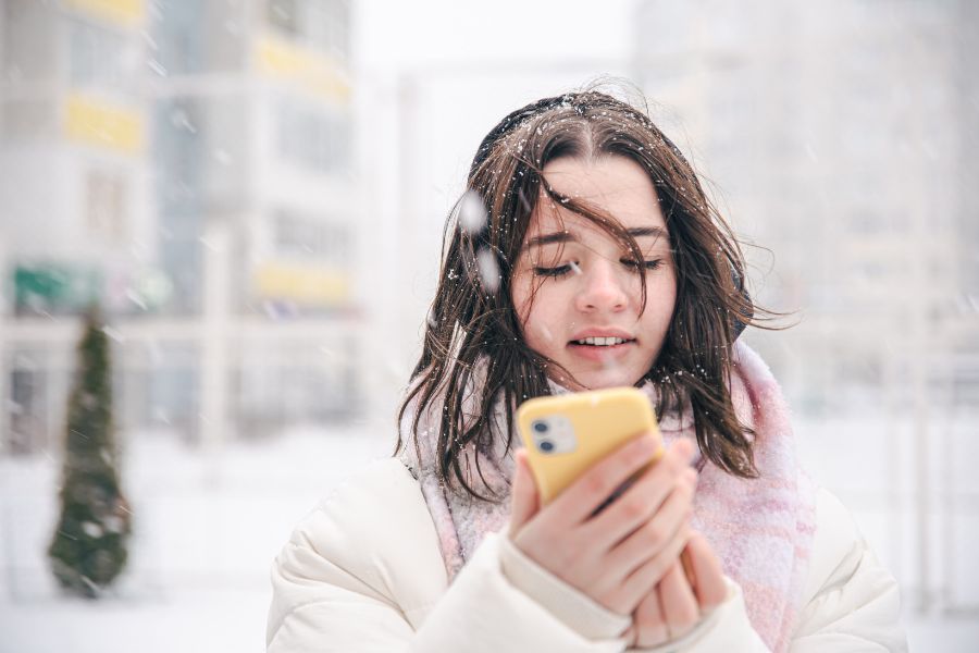 Teen checking snow day forecast on phone during snowfall in Canada