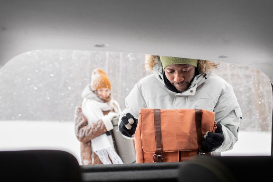 Family preparing car with winter supplies on a snowy day in Canada — essential gear for safety, warmth, and travel readiness.
